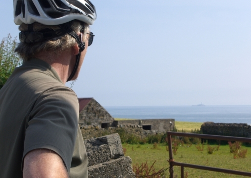 A cyclist, a meadow, an old farm house and the sea.